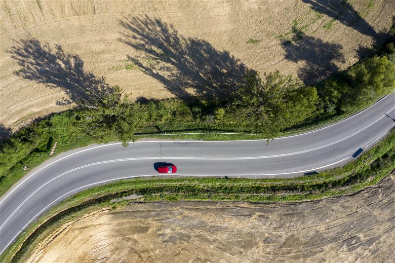 Imagen de un coche rojo en una carretera interurbana 